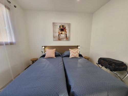 a bedroom with a blue bed with two pillows at La grange d'augustin in Saint-Thibéry