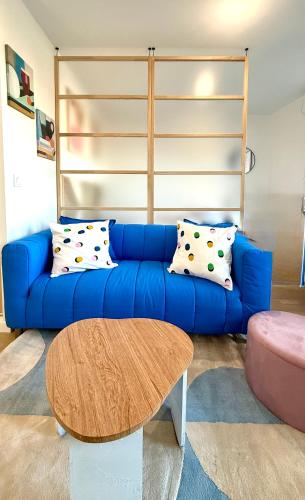 a blue couch with pillows in a living room at La maison colorée proche de Paris in Romainville