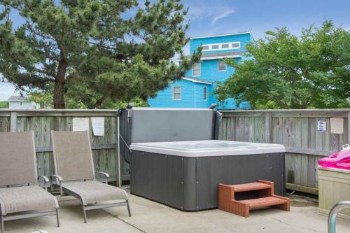 a hot tub on a patio with chairs and a blue house at Fish Tank in Corolla
