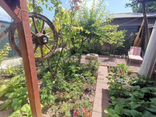 ein Garten mit einem Wagenrad und einigen Pflanzen in der Unterkunft Căsuța din grădină in 2 Mai