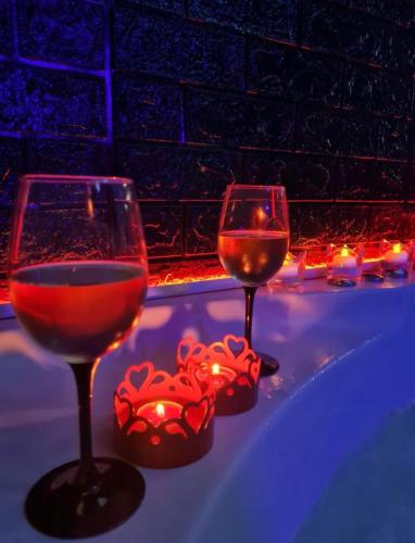 two glasses of wine sitting on a table with lights at Chata Drwala w Rynku -Duża Wanna -Klima ,1-4 Os -Car Park Faktura in Kielce