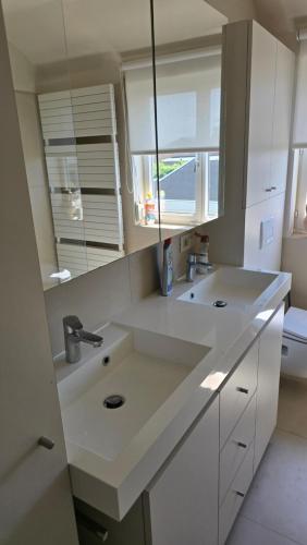 a white kitchen with a sink and a window at Sea Home in Middelkerke