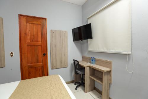 a room with a desk and a tv on a wall at Hotel Los Altos Express "La Centroamerica" in Managua