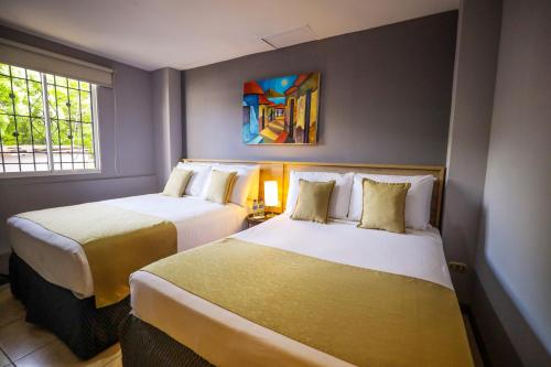 a hotel room with two beds and a window at Hotel Los Altos Express "La Centroamerica" in Managua