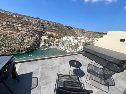 a balcony with a table and chairs and a view of a city at GOZO DIVE Residence in Xlendi