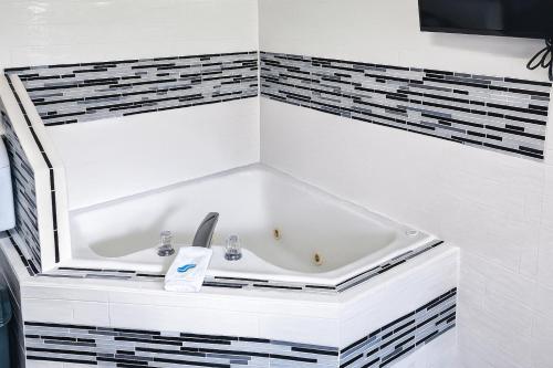 a bathroom with a tub with black and white tiles at Catalina Airport Motel in Sterling Heights