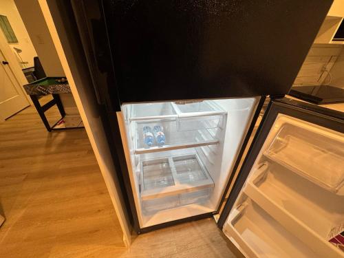 an empty refrigerator with its door open in a kitchen at Cozy Apartment close to Moncton Airport in Dieppe