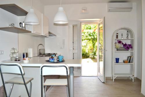 a kitchen with a white counter and chairs in it at Porticciolo in San Vito