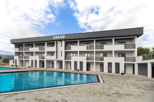 a building with a swimming pool in front of it at GRAND Hotel NEW 2025 in Solotvyno