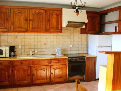 - une cuisine avec des placards en bois, un évier et une cuisinière dans l'établissement Ferme Pédagogique " L'Bout d'Chemin", à Genevreuille