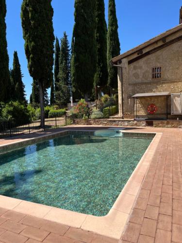 a swimming pool in front of a house with trees at Podere Le Grotte in San Gimignano