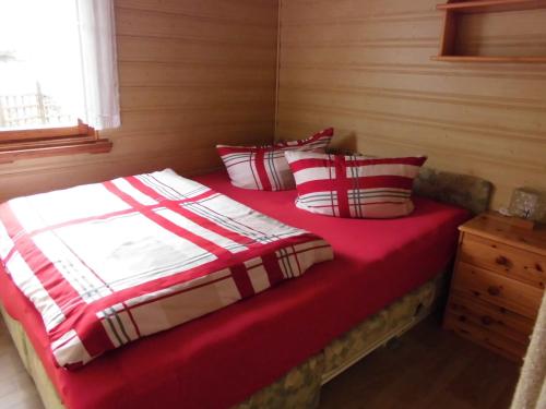 a bedroom with a bed with red sheets and pillows at Gartenlandhaus in Dohma