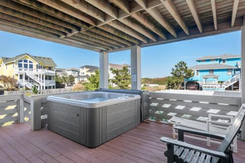 a hot tub on a deck with a chair at Fun2Sea in Corolla