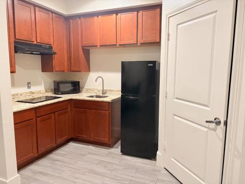 a kitchen with a black refrigerator and wooden cabinets at Americas Best Value Inn Houston Veterans Memorial in Houston
