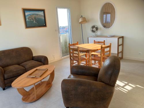 un salon avec un canapé, une table et des chaises dans l'établissement le 5ème ASTRO - vue mer et chenal, à La Chaume