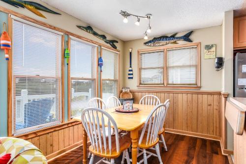 a dining room with a table and chairs and windows at Gone Fishin in Nags Head