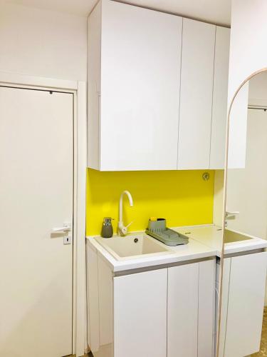 a kitchen with a sink and a yellow accent wall at Happy Sweet Apartment in Niš