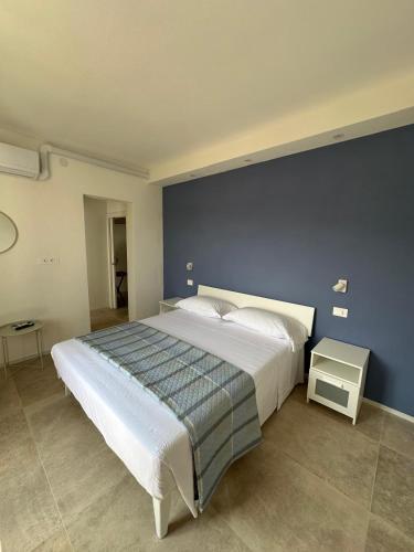 a bedroom with a large bed with a blue wall at Villa Viola Rooms, a 200mt dalla spiaggia di Procchio in Procchio