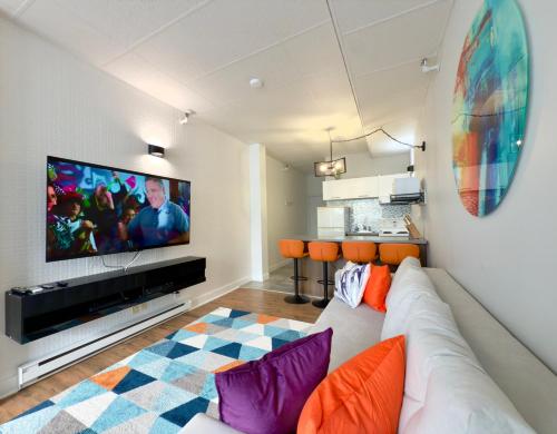 een woonkamer met een witte bank en een flatscreen-tv bij Refuge Urbain Quebec - Lofts de la Cité in Québec