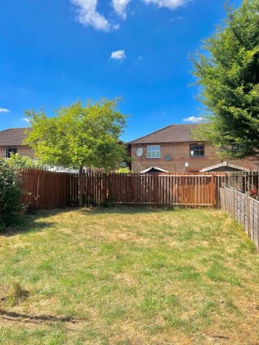 a wooden fence in front of a yard at Central MK Home, Garden and Free Private Driveway Parking! 4 Beds Fully Equipped Train station 5 Mins in Milton Keynes