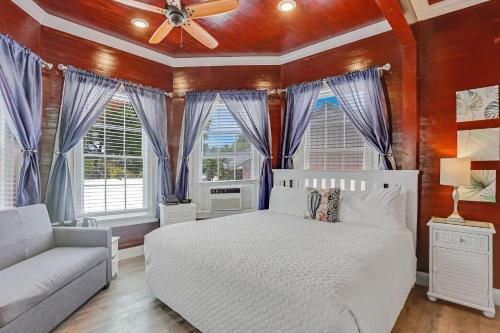 a bedroom with a white bed and a couch and windows at The Palms Hotel in Key West