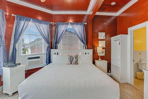 a bedroom with a white bed and a red wall at The Palms Hotel in Key West