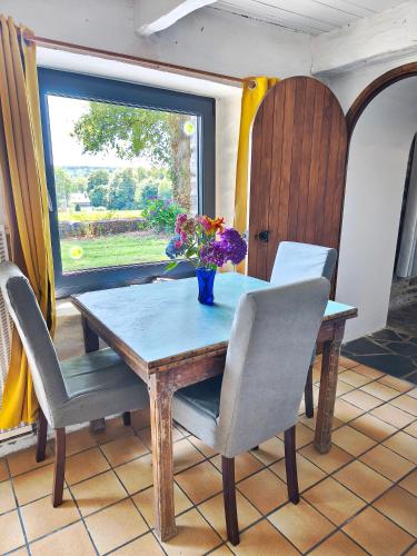 a table and chairs with a vase of flowers on it at Gîte Lann Avel Classé 3 étoiles WIFI CALME CAMPAGNE in Laniscat