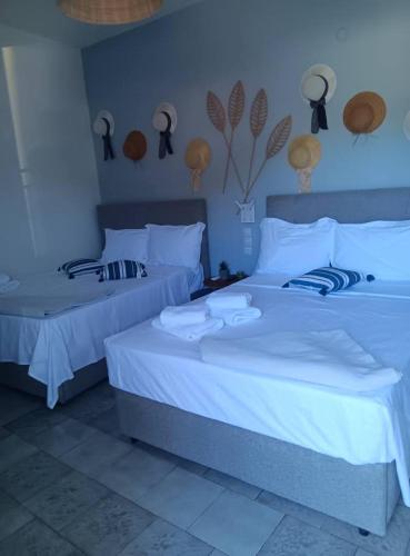 two beds in a room with white sheets at galazio in Khorió Akhíllion