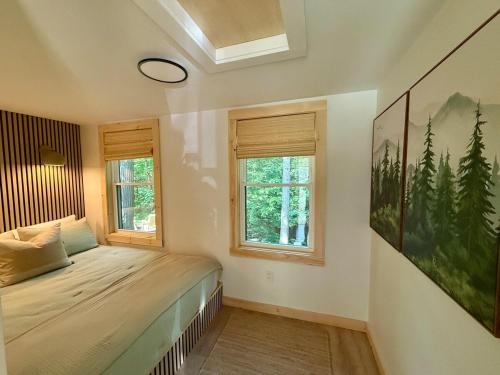 a bedroom with a bed and two windows at BrookHaus - Modern Cabin Stay at Harvard Brook in Lincoln
