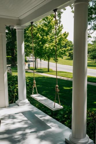 Un porche con dos columpios en una casa blanca. en The Maidstone Inn, en East Hampton