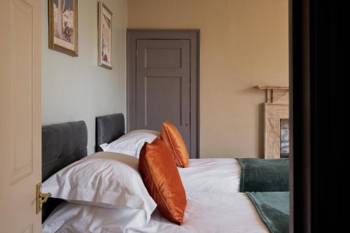 a bedroom with two beds with orange and white pillows at Walcot Townhouse 3 bedroom in Bath