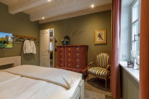 a bedroom with a bed and a dresser and a chair at Landhaus-zum-Wieseneck in Ilsenburg