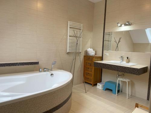 a bathroom with a large tub and a sink at Ostoja Dziarnówko - willa z ogrodem na Mazurach in Iława
