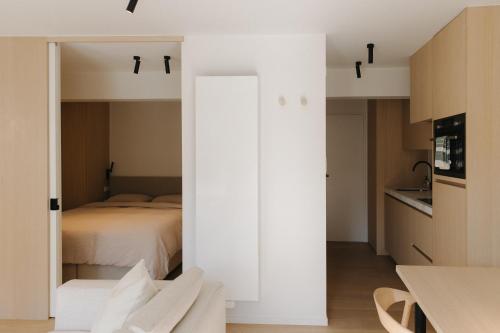 a white bedroom with a bed and a kitchen at Studio Lou in Knokke-Heist