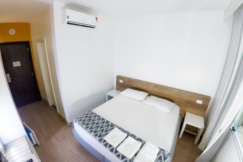 a small bedroom with a white bed in a room at Hotel Innove Guaíba in Guaíba