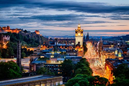 a city skyline with a clock tower at night at Black Ivy in Edinburgh