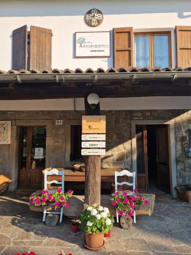 a building with two chairs and a table with flowers at Agriturismo Il Respiro del Bosco in San Piero in Bagno