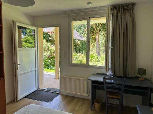 a room with a desk and a window and a door at Logis Hôtel La Demeure du Perron in Quettehou