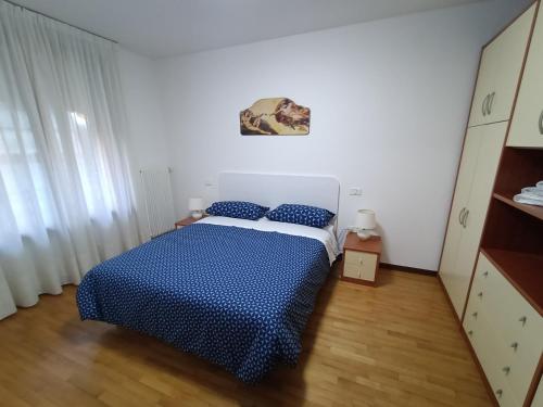 ポルデノーネにあるLittle Suiteの白い部屋に青いベッドが備わるベッドルーム1室