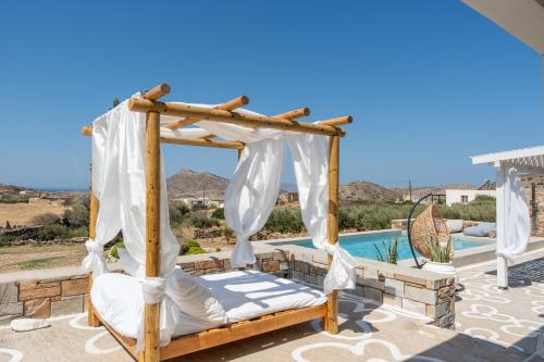 a canopy bed on a patio next to a pool at Revery Villa in Ios Chora