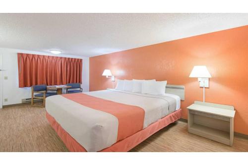 a hotel room with a large bed with orange walls at Motel 6 Gold Beach in Gold Beach
