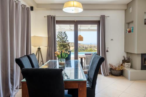 a dining room with a glass table and chairs at Revery Villa in Ios Chora