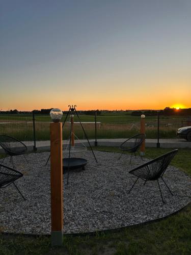 a playground with chairs and a swing at sunset at Stodoła Sople 2 in Sople