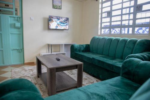 a living room with a green couch and a table at Neema Suites in Rungiri