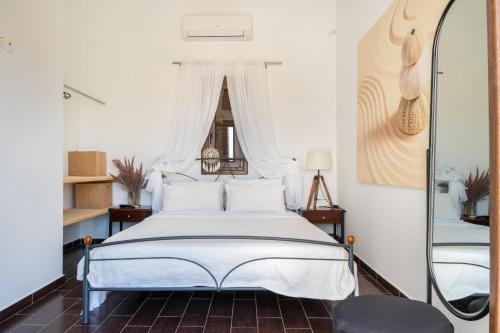 a bedroom with a white bed and a mirror at Revery Villa in Ios Chora
