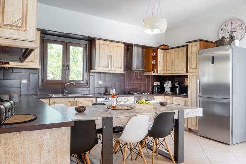 a kitchen with a large island with chairs and a refrigerator at Revery Villa in Ios Chora