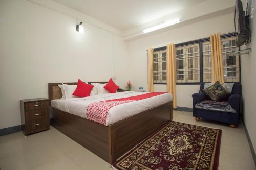 a bedroom with a large bed and a chair at Hotel O Ghakhel in Ravangla
