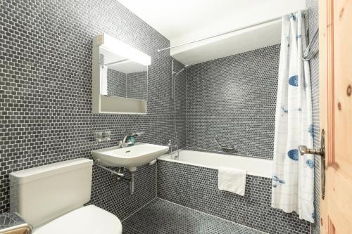 a bathroom with a sink and a toilet and a tub at Chesa Michel in Bever