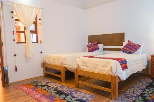 a bedroom with two beds and a window at La Rosa Wellness Lodge in Urubamba