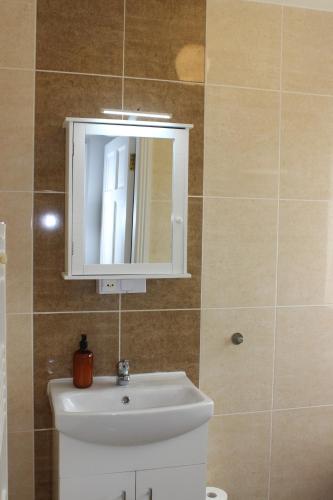 a bathroom with a white sink and a mirror at Family Home, 20 mins from Youghal Beach in Killeagh